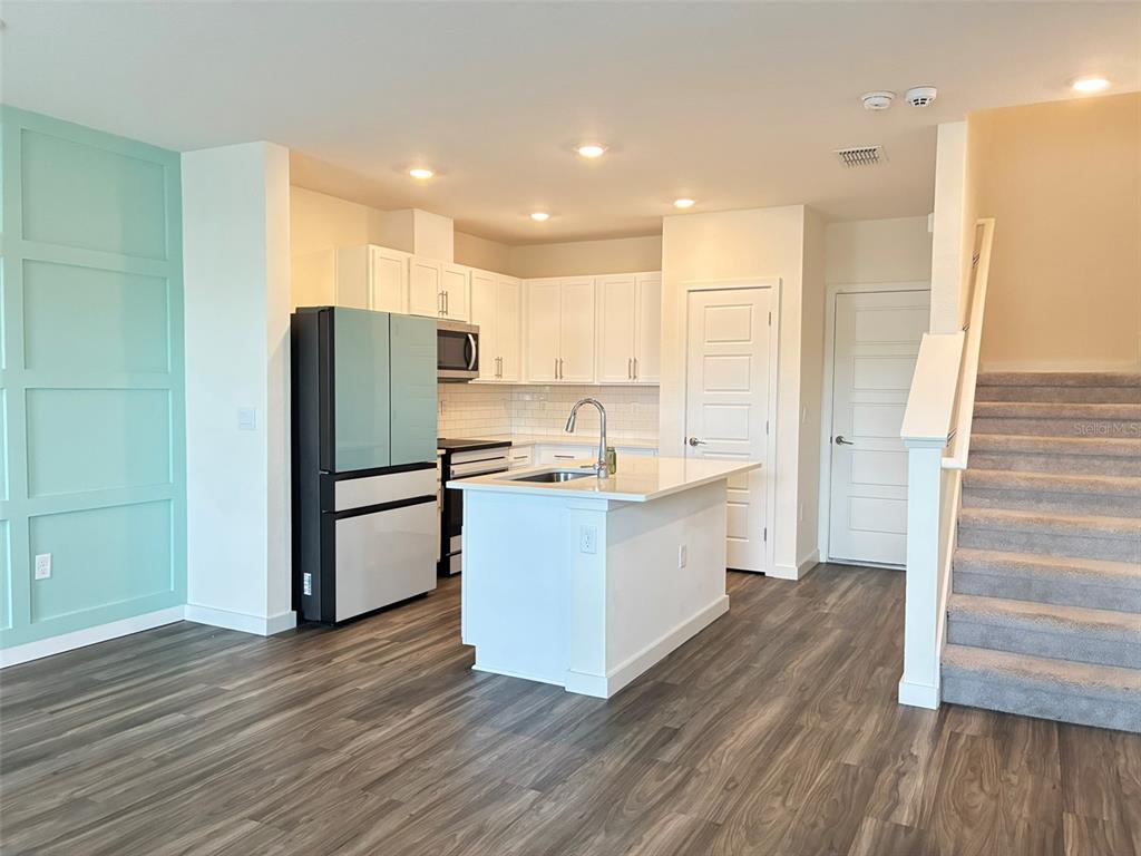 A kitchen with white cabinets, a central island, and a light blue accent wall — 553 JOHN L MICA WAY, LONGWOOD, FL