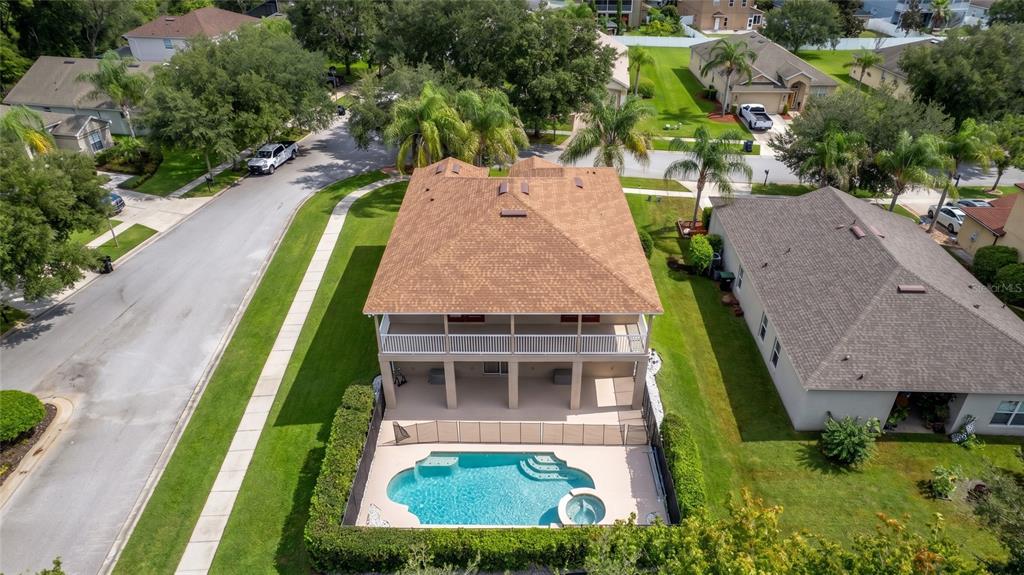 An aerial view of a two-story house with a balcony, swimming pool, and fenced yard — 5890 ANSLEY WAY, MOUNT DORA, FL