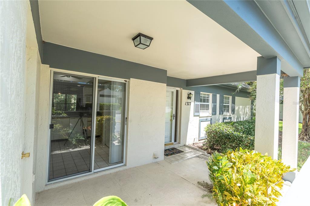 A covered front porch with a sliding glass door, a front entrance, and landscaping — 1377 N MCMULLEN BOOTH ROAD, CLEARWATER, FL