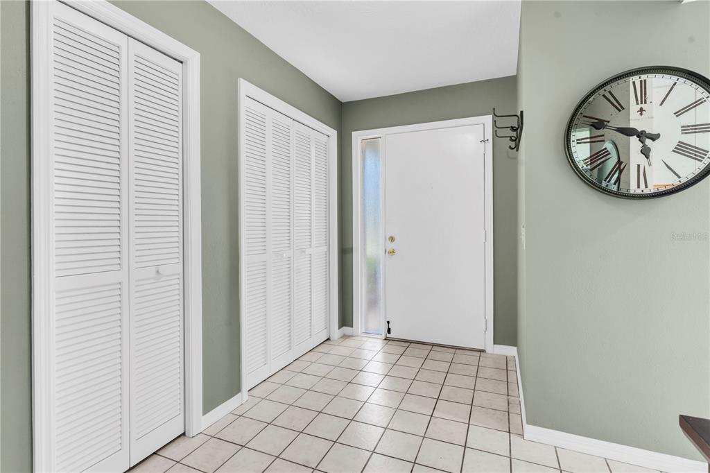 An entryway features white louvered closet doors, a white front door, and light-colored tile flooring — 1377 N MCMULLEN BOOTH ROAD, CLEARWATER, FL