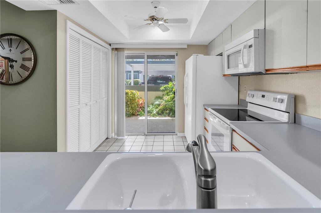 A kitchen with white appliances, gray countertops, and a sliding glass door to the outside — 1377 N MCMULLEN BOOTH ROAD, CLEARWATER, FL