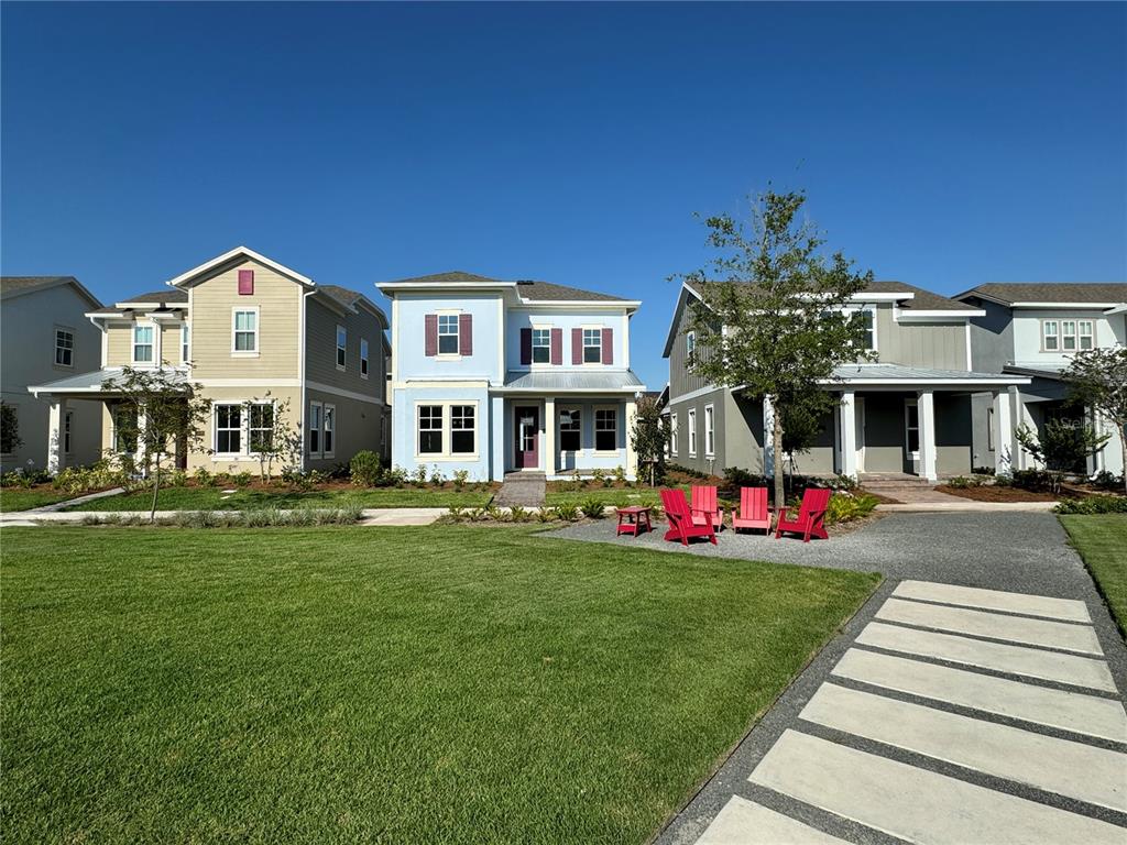 Three suburban houses stand behind a green lawn with a gravel patio and red chairs — 13352 LEGGETT ALLEY, ORLANDO, FL