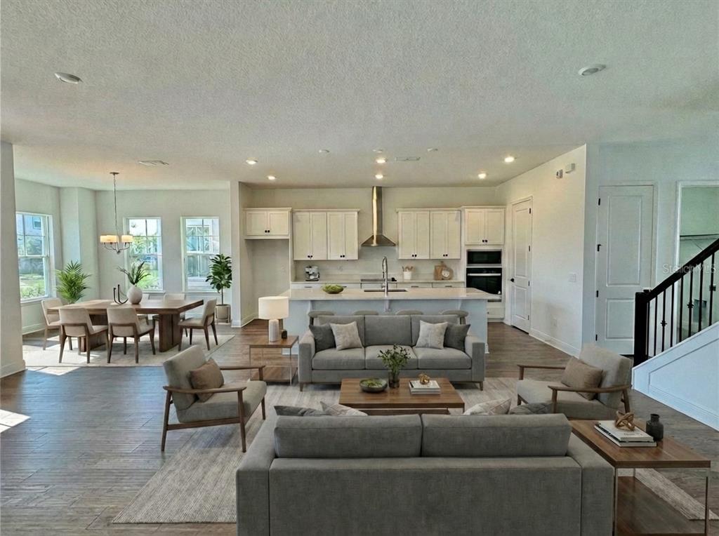 An open-concept living room and kitchen featuring gray furniture, light wood floors, and white cabinetry — 13352 LEGGETT ALLEY, ORLANDO, FL