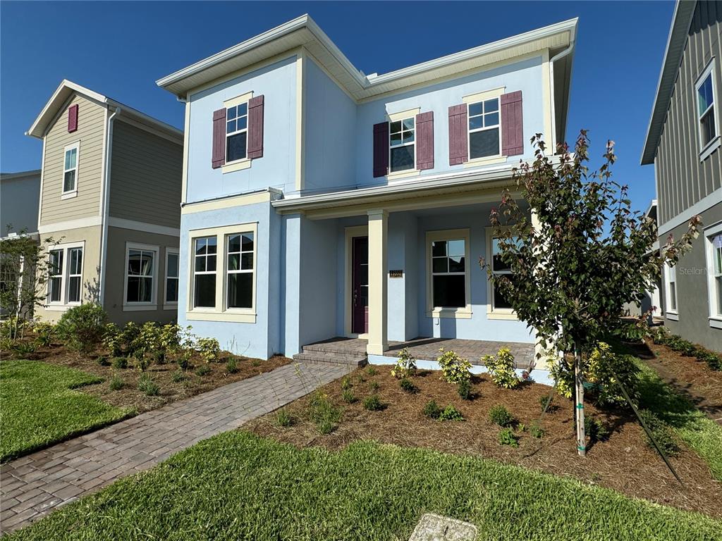 A two-story light blue house with a covered front porch and a brick walkway — 13352 LEGGETT ALLEY, ORLANDO, FL