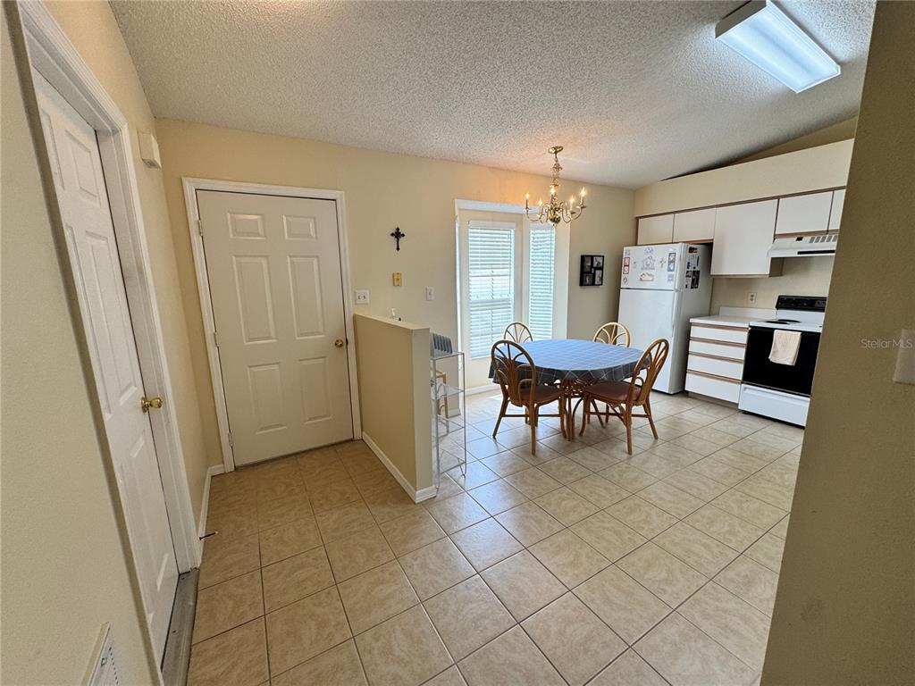 A kitchen and dining area with tile floors, white cabinets, and a round wooden table — 25220 WILD HERON, LEESBURG, FL