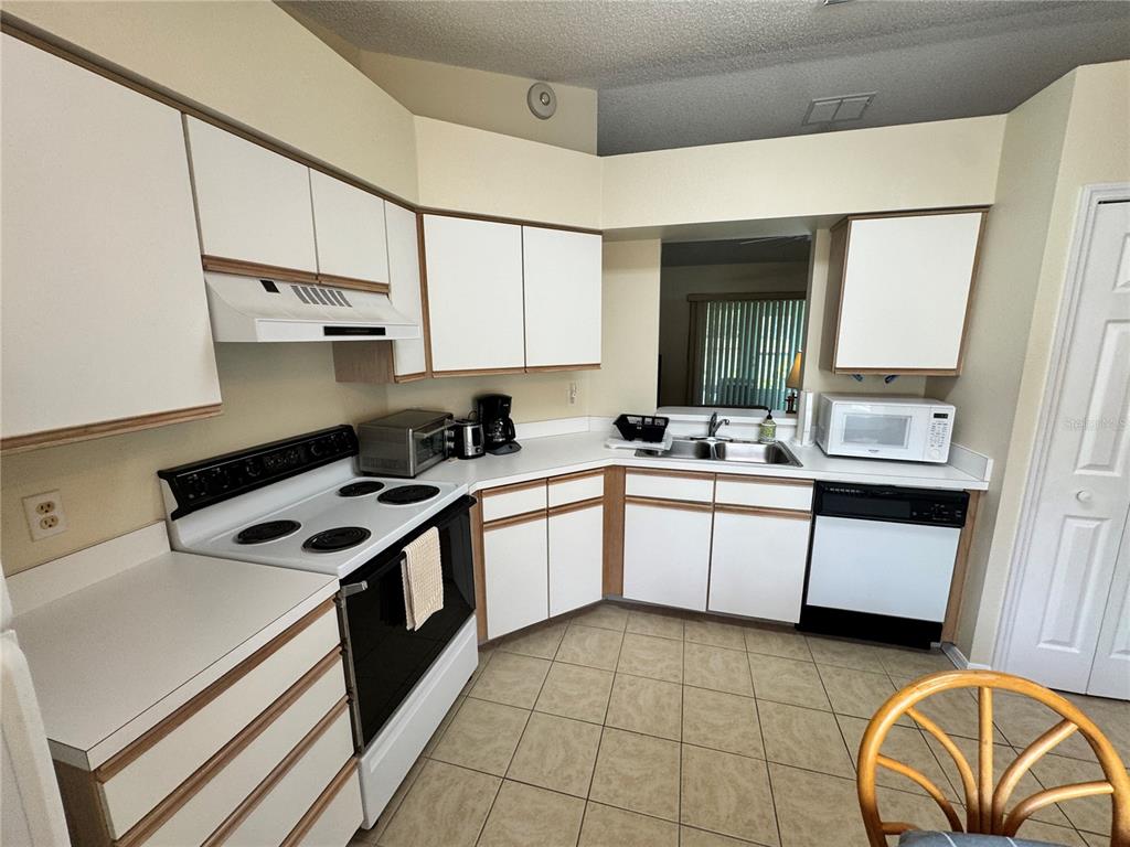 A kitchen with white cabinets, laminate countertops, a white stove, and tiled flooring — 25220 WILD HERON, LEESBURG, FL