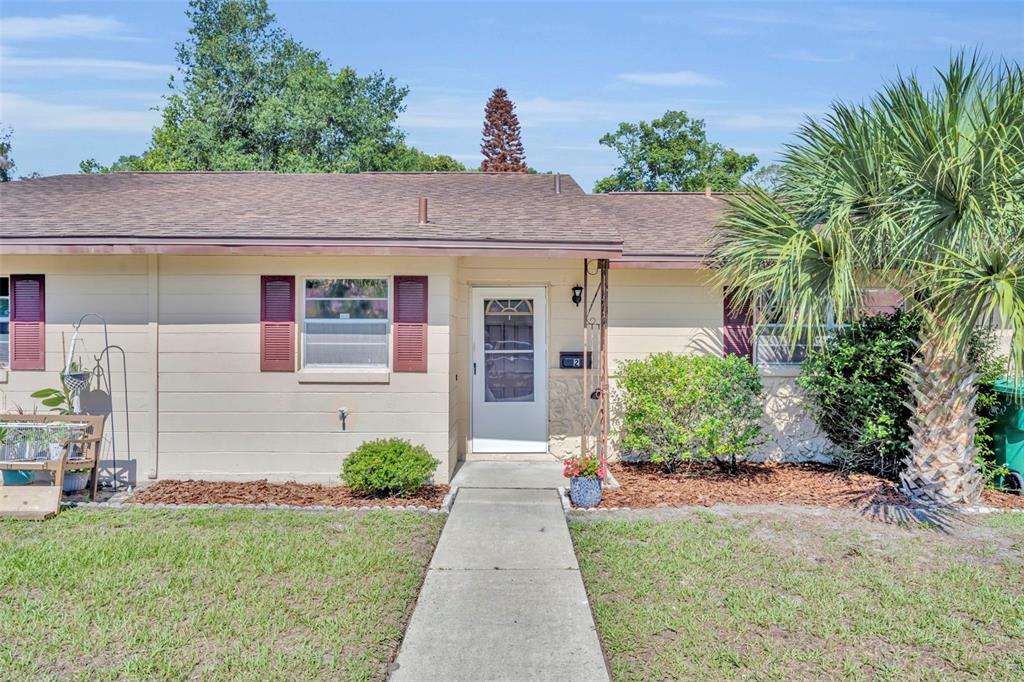 A kitchen features white cabinets, a white countertop, a sink under a window, and wood flooring — 2 VILLA VILLAR COURT UNIT 20, DELAND, FL