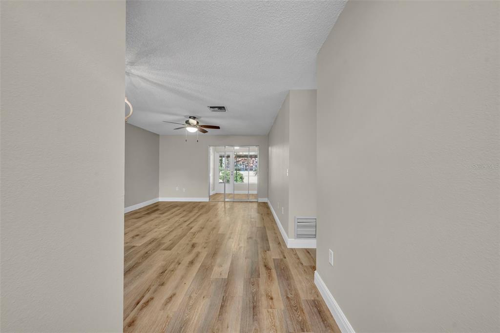 A modern kitchen features white cabinets, stainless steel appliances, and light wood-look flooring — 2 VILLA VILLAR COURT UNIT 20, DELAND, FL