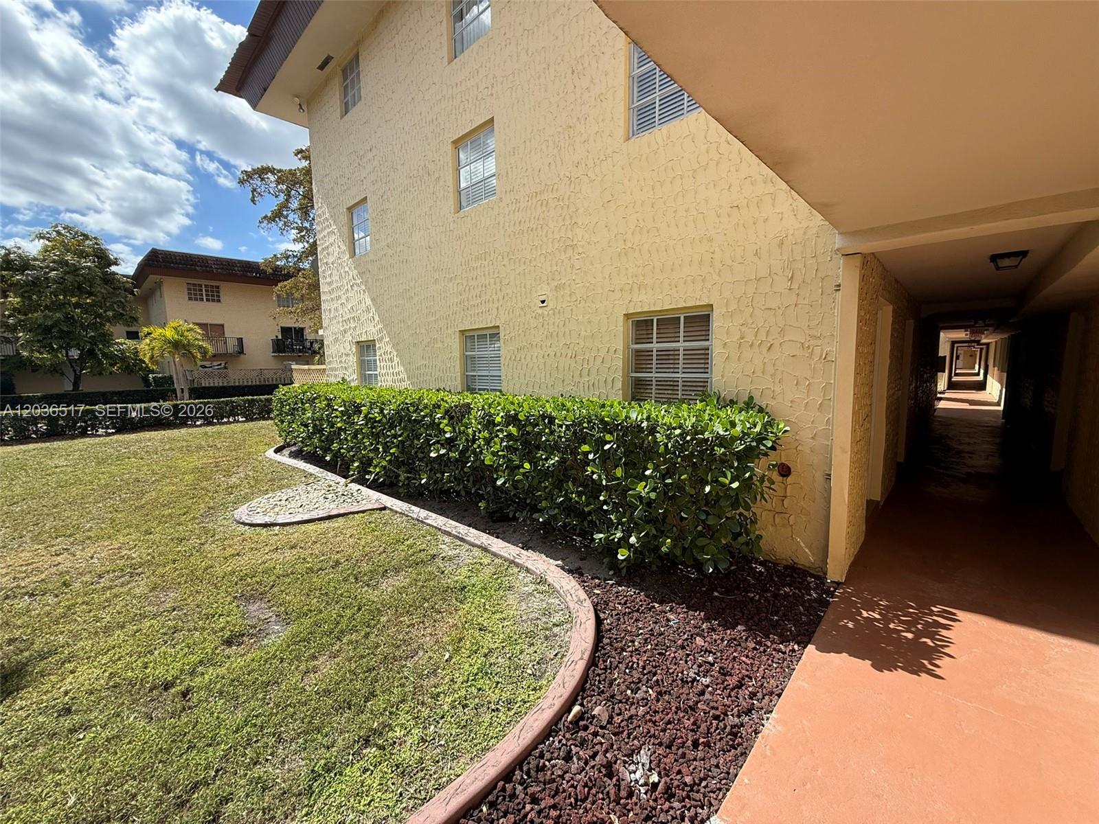 The exterior of a multi-story yellow building features a landscaped hedge and a covered walkway — 8500 SW 109th Ave # 109, Miami FL 33173, MIAMI, FL