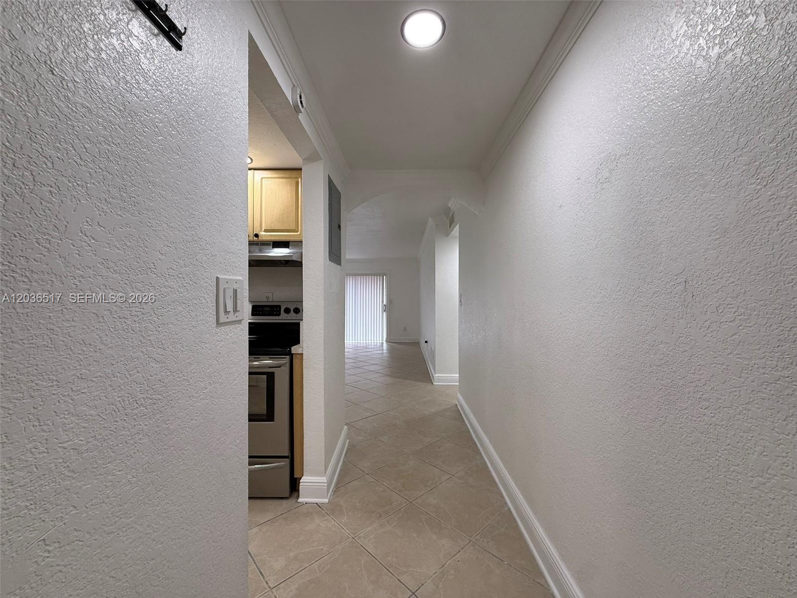 A hallway with tile flooring leads toward a kitchen and a bright living area — 8500 SW 109th Ave # 109, Miami FL 33173, MIAMI, FL