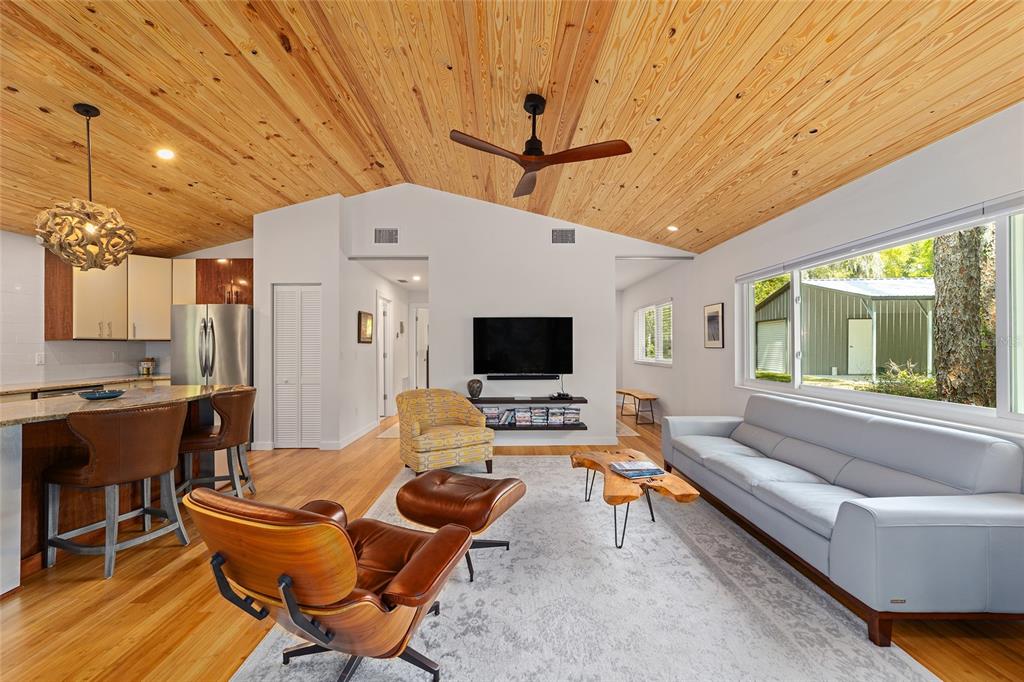 A living room with a wood-paneled vaulted ceiling, a light gray sofa, and leather chairs — 10894 SW 185TH TERRACE, DUNNELLON, FL