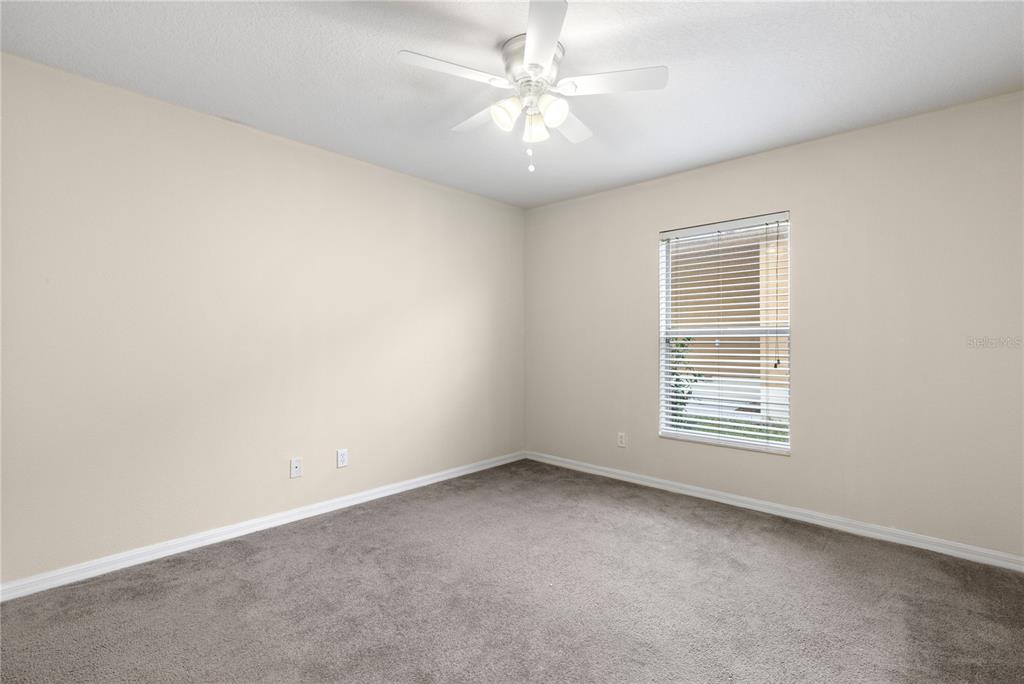 A bedroom with beige walls, gray carpeting, a ceiling fan, and a single window — 20011 NOB OAK AVENUE, TAMPA, FL