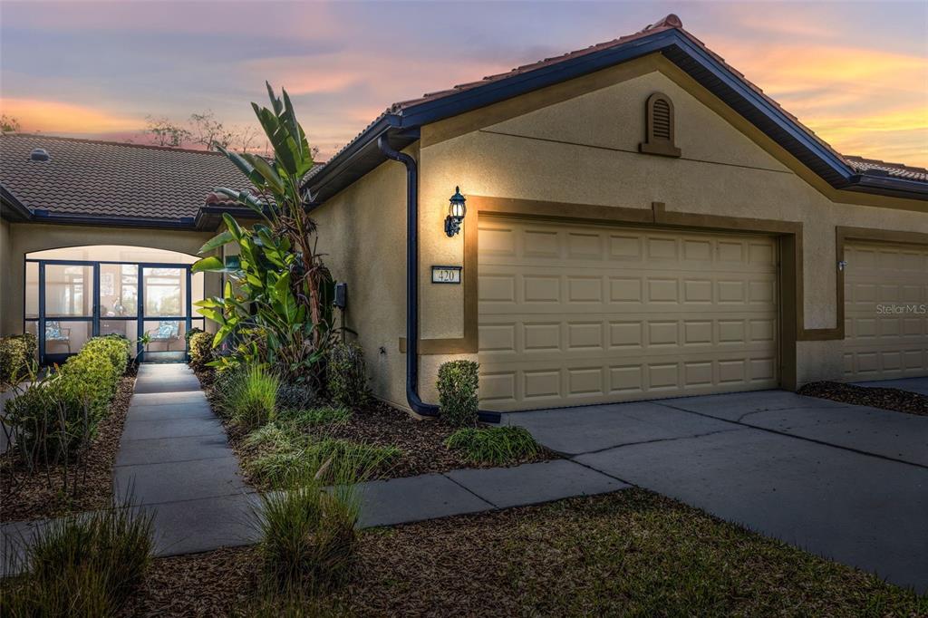 A tan stucco house exterior features a two-car garage, a tiled roof, and a walkway — 420 SENECA FALLS DRIVE, APOLLO BEACH, FL
