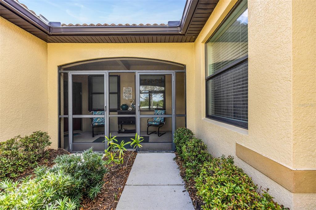 A concrete walkway leads to a screened-in front entryway with a yellow stucco exterior — 420 SENECA FALLS DRIVE, APOLLO BEACH, FL
