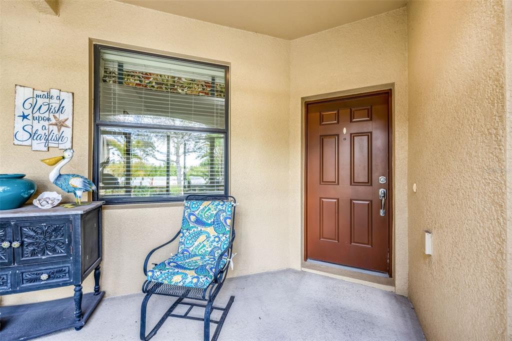 A covered entryway features a brown front door, a window, and a chair — 420 SENECA FALLS DRIVE, APOLLO BEACH, FL