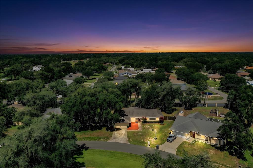 An aerial view of a suburban neighborhood at sunset featuring two single-story homes — 7716 NATURE TRAIL, LAKELAND, FL