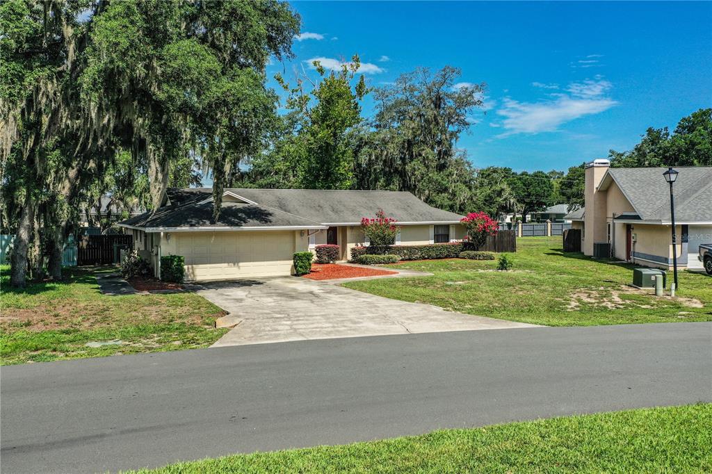 A single-story house with a beige exterior, a two-car garage, and a concrete driveway — 7716 NATURE TRAIL, LAKELAND, FL