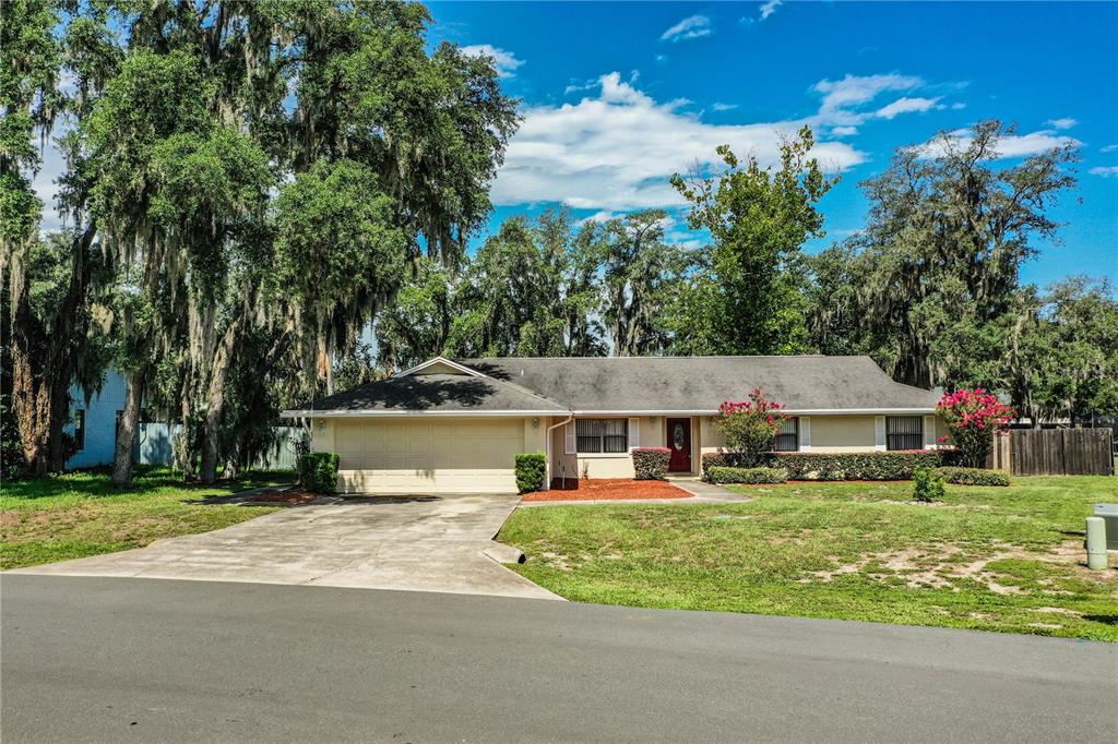 A single-story house with a beige exterior, a two-car garage, and a concrete driveway — 7716 NATURE TRAIL, LAKELAND, FL