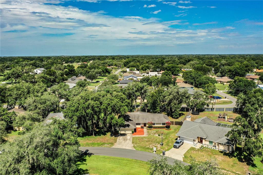 An aerial view shows two suburban houses with driveways surrounded by trees and green lawns — 7716 NATURE TRAIL, LAKELAND, FL