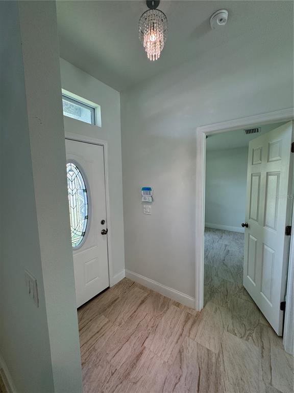 An entryway features a white front door with a glass insert, tile flooring, and a chandelier — 2888 FOXDALE DRIVE, DELTONA, FL
