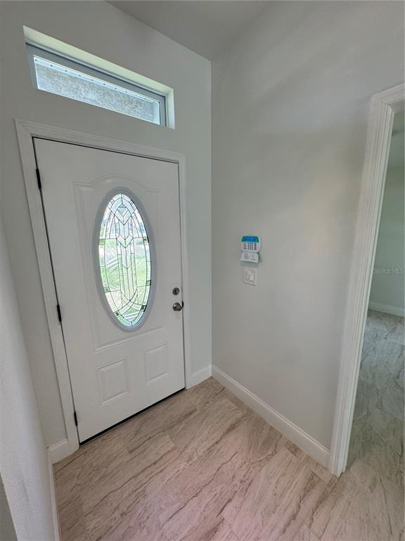 An entryway features a white front door with an oval glass insert and tile flooring — 2888 FOXDALE DRIVE, DELTONA, FL