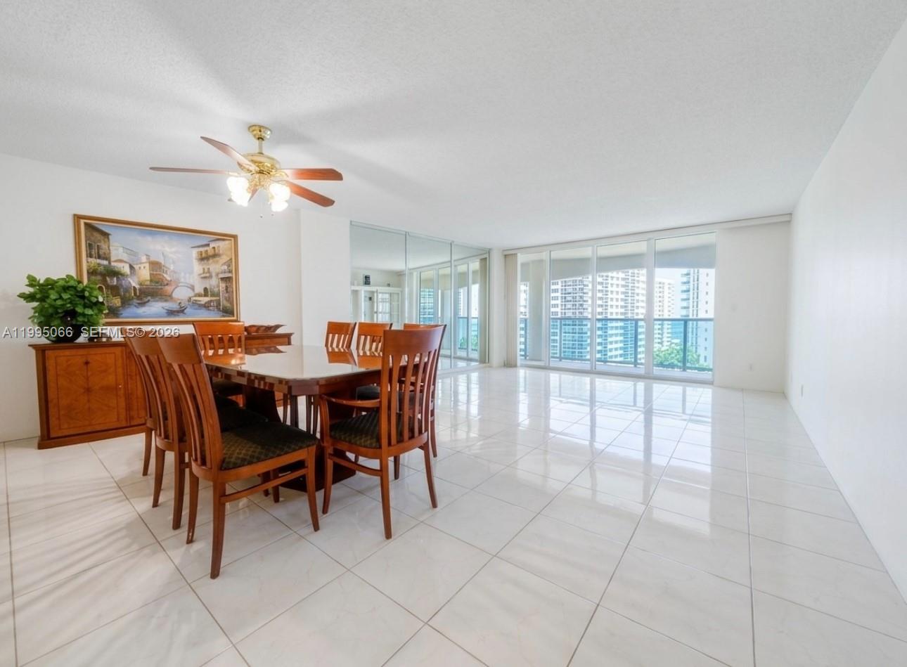 A dining room with a wooden table, chairs, tile floors, and floor-to-ceiling windows — 3800 S Ocean Dr # 816, Hollywood FL 33019, HOLLYWOOD, FL