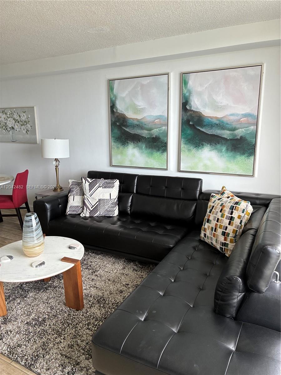 A living room features a black leather sectional sofa, a marble coffee table, and wall art — 2000 NE 135th St # 710, North Miami FL 33181, NORTH MIAMI, FL
