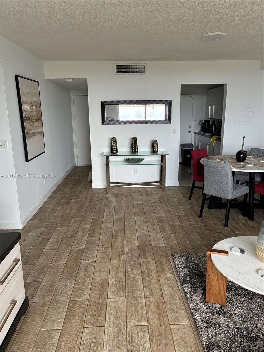 A dining area and entryway feature wood-look tile flooring, a console table, and a mirror — 2000 NE 135th St # 710, North Miami FL 33181, NORTH MIAMI, FL