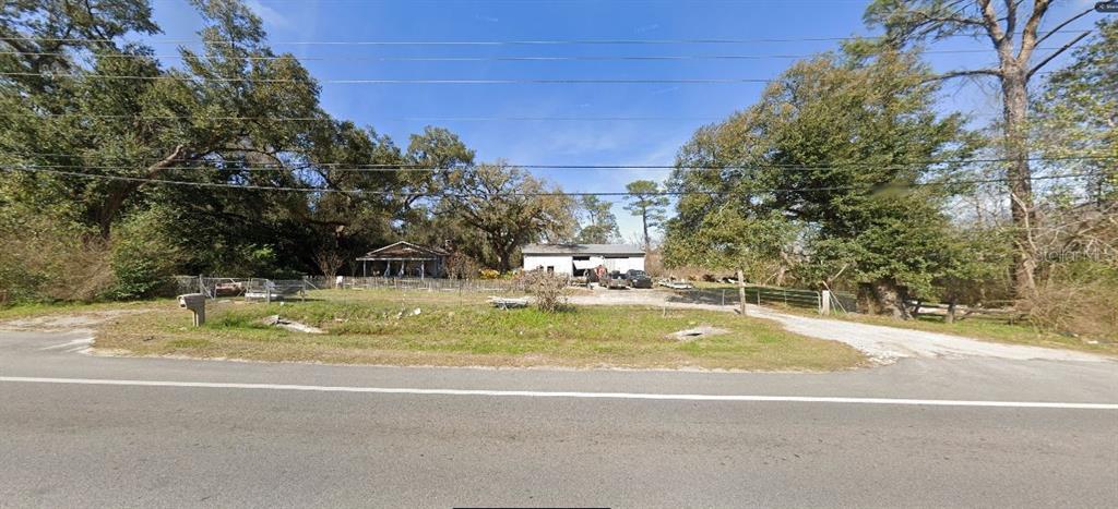 A small house and a detached garage sit on a grassy lot with mature trees — 720 E OLIVE ROAD, PENSACOLA, FL