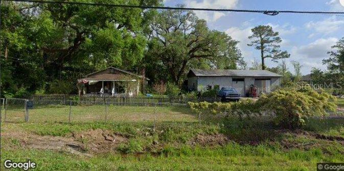 A small house and a detached metal garage sit on a grassy lot with trees — 720 E OLIVE ROAD, PENSACOLA, FL