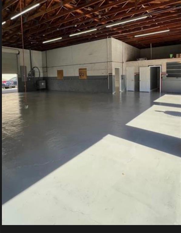 An empty industrial warehouse space features a gray epoxy floor and exposed wooden ceiling beams — 7809 CLARK MOODY BOULEVARD, PORT RICHEY, FL