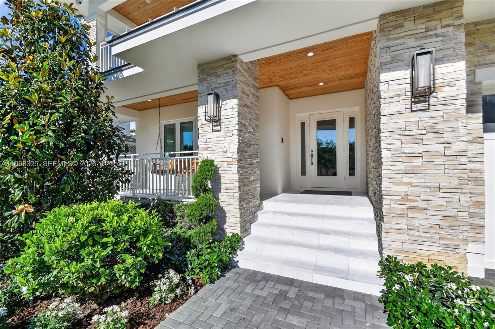 The exterior of a modern house features stone pillars, a wooden ceiling, and white steps — 1017 S Palmway, Lake Worth FL 33460, LAKE WORTH, FL