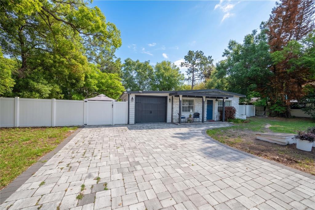 A single-story house with a white stone facade, dark garage door, and a paved driveway — 291 IVEY ROAD, CASSELBERRY, FL