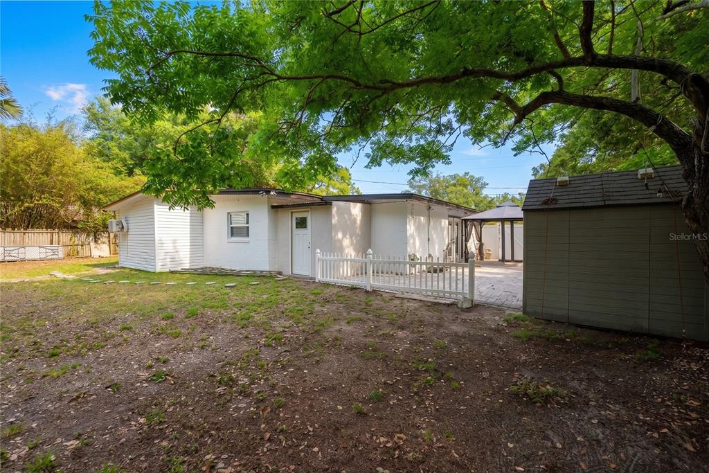 A white house with a fenced patio and a shed sits in a grassy backyard — 291 IVEY ROAD, CASSELBERRY, FL