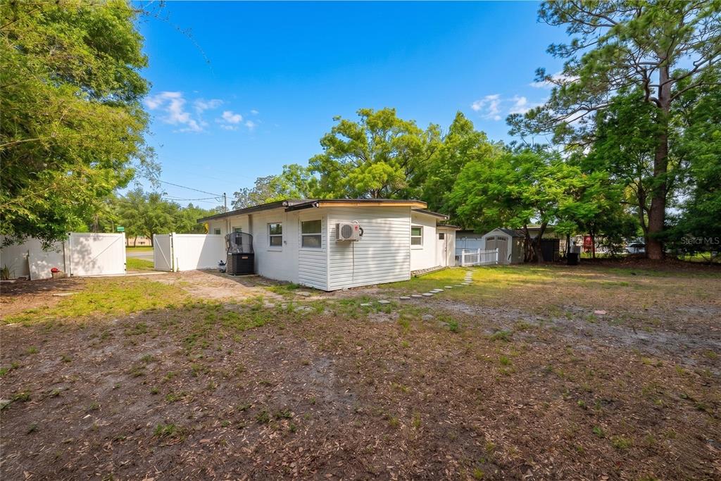 A white, single-story house with a flat roof sits on a large, grassy lot — 291 IVEY ROAD, CASSELBERRY, FL