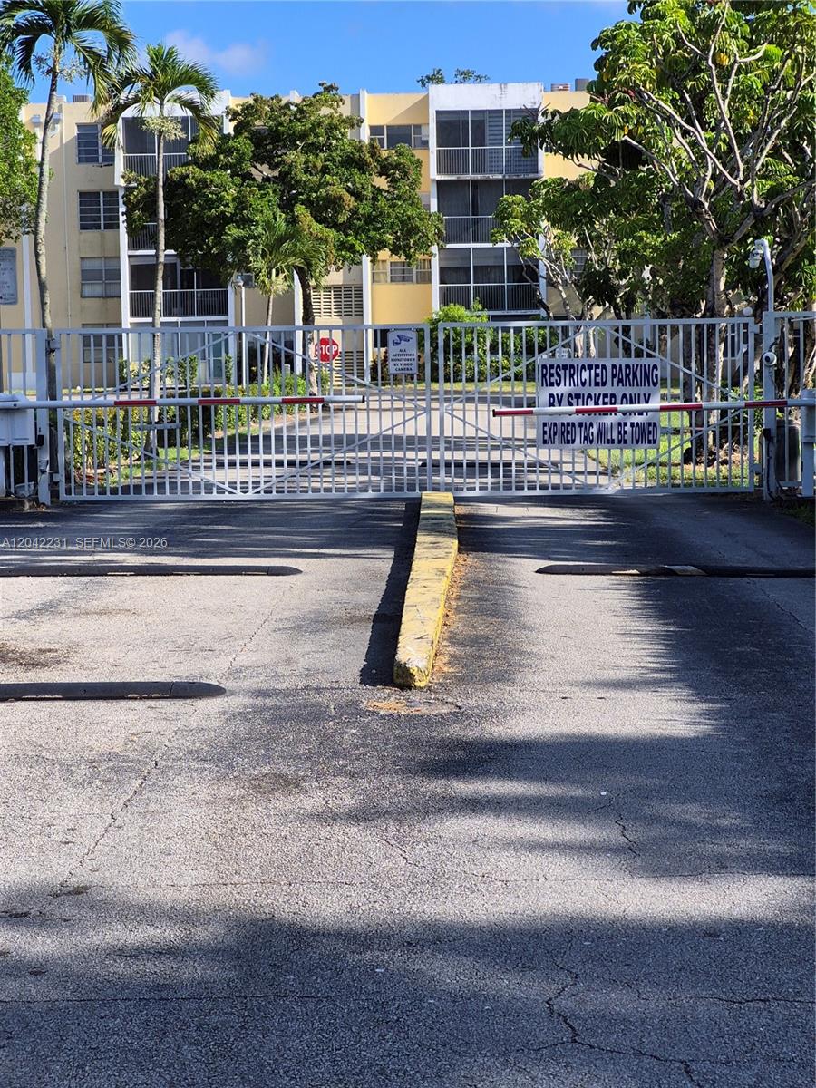 A gated entrance with a restricted parking sign leads to a multi-story apartment building — 942 NE 199th St # 4G, Miami FL 33179, MIAMI, FL