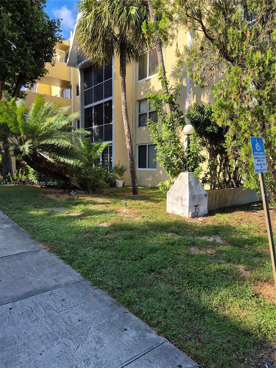 A multi-story yellow apartment building with a palm tree and a handicap parking sign — 942 NE 199th St # 4G, Miami FL 33179, MIAMI, FL