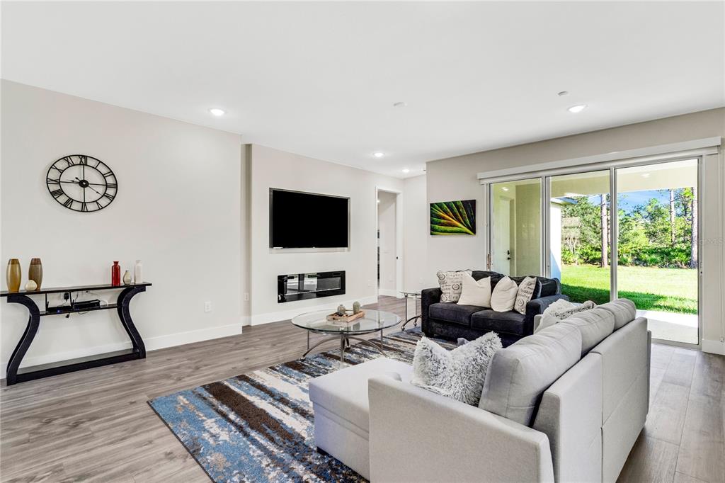 An open-concept living room and kitchen feature gray wood-look flooring and a large area rug — 3724 CORONET AVENUE, ORLANDO, FL