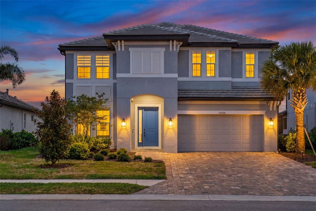 A two-story gray house with a blue front door and a paved driveway at dusk — 17510 SAVORY MIST CIRCLE, BRADENTON, FL