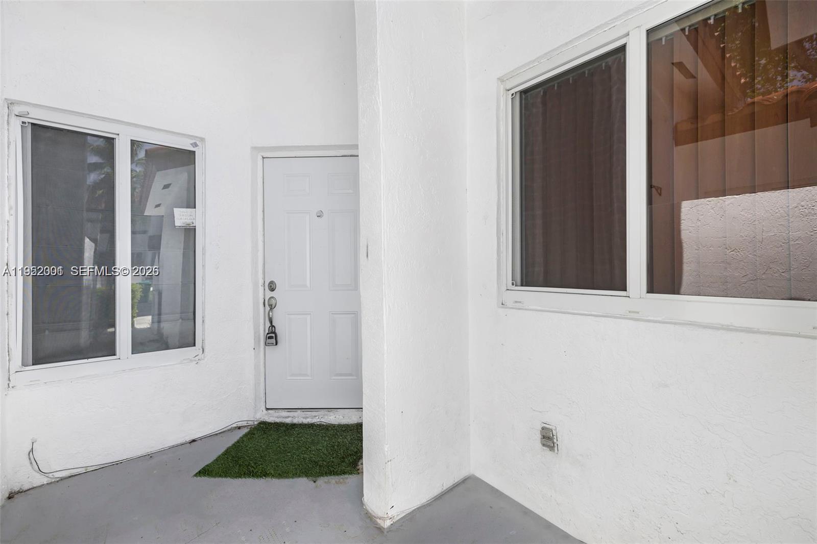 A white exterior door is flanked by two windows on a covered patio area — 8421 SW 209th St # 8421, Cutler Bay FL 33189, CUTLER BAY, FL