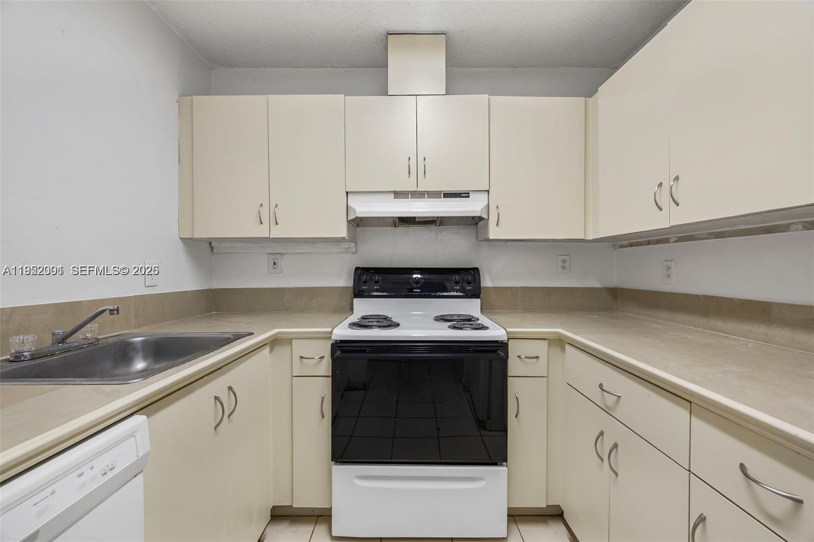 A kitchen features off-white cabinets, a black and white stove, and a stainless steel sink — 8421 SW 209th St # 8421, Cutler Bay FL 33189, CUTLER BAY, FL