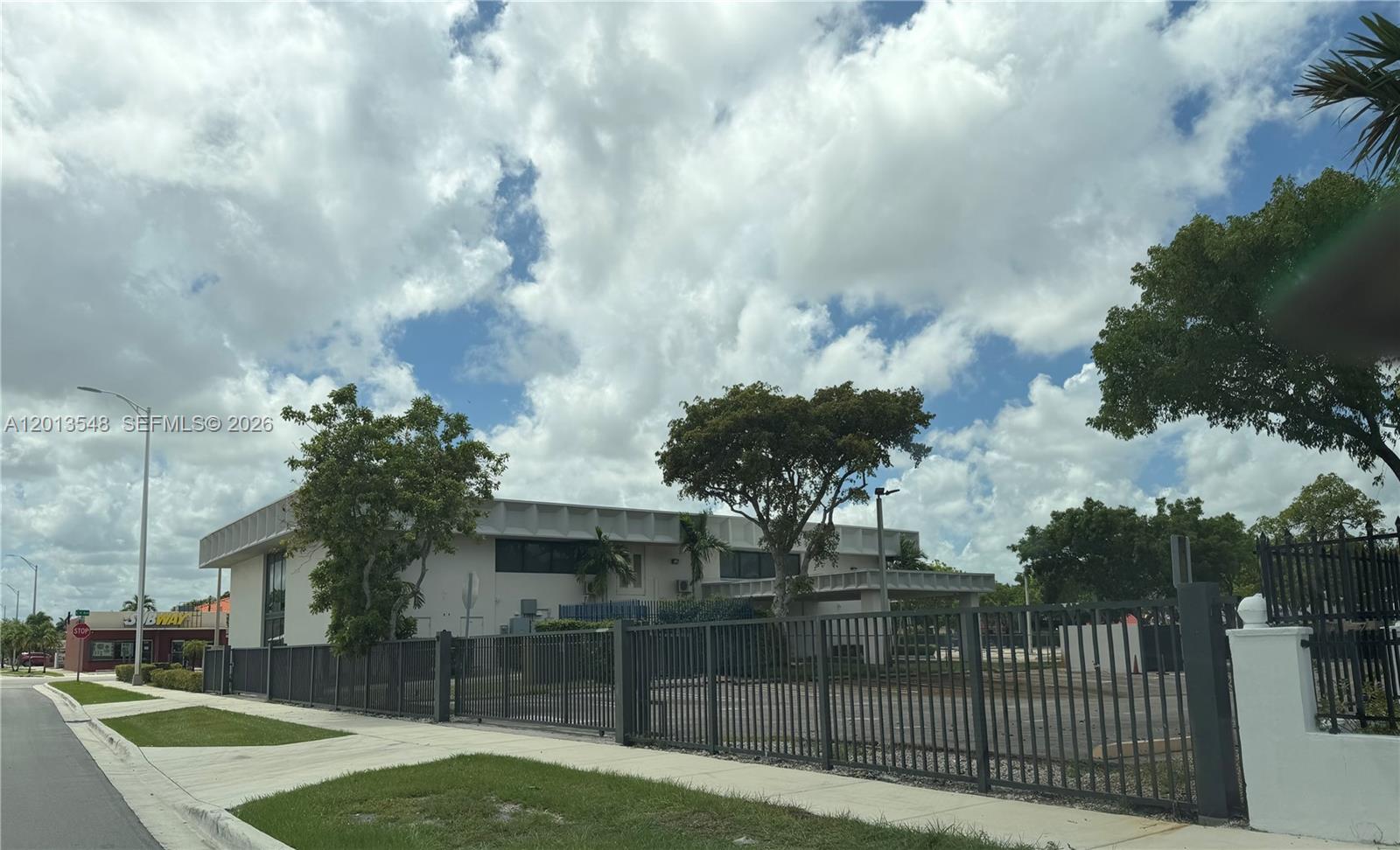 A two-story commercial building sits behind a metal fence with a parking lot — 1601 E 4th Ave, Hialeah FL 33010, HIALEAH, FL