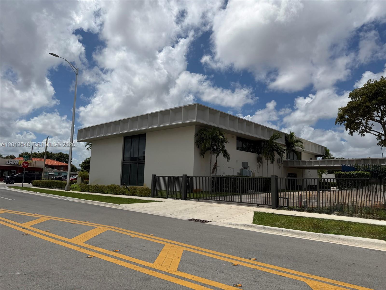 A two-story commercial building with a flat roof and a metal fence stands outdoors — 1601 E 4th Ave, Hialeah FL 33010, HIALEAH, FL