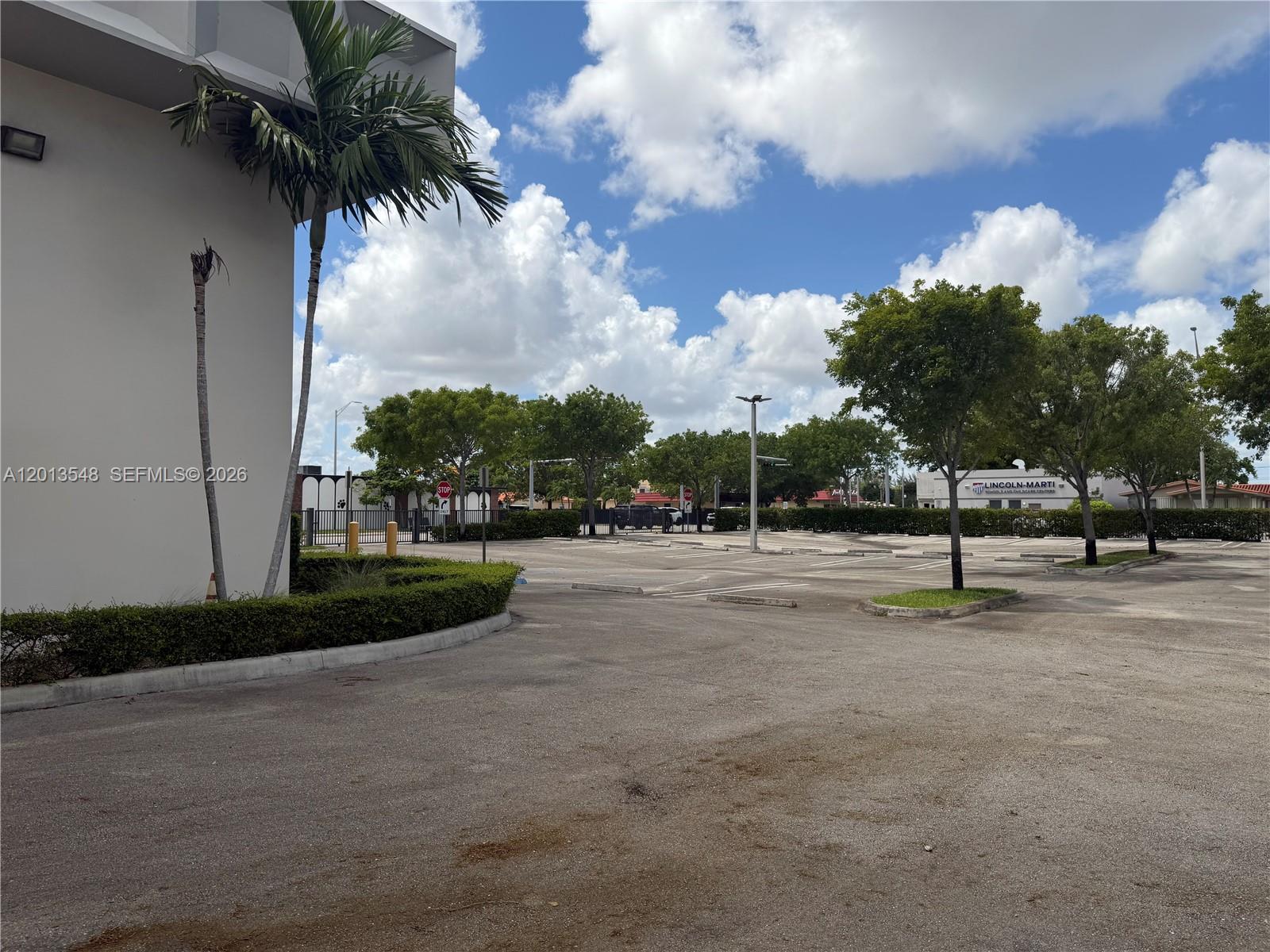 A paved parking lot sits in front of a building with palm trees and landscaping — 1601 E 4th Ave, Hialeah FL 33010, HIALEAH, FL