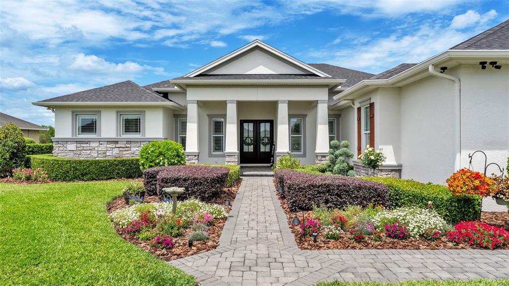 A single-story house features a stone-accented facade, a paved walkway, and manicured landscaping — 6509 HERITAGE PARK PLACE, LAKELAND, FL