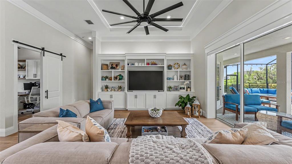 A living room features a large sectional sofa, built-in shelving, and a sliding glass door — 6509 HERITAGE PARK PLACE, LAKELAND, FL