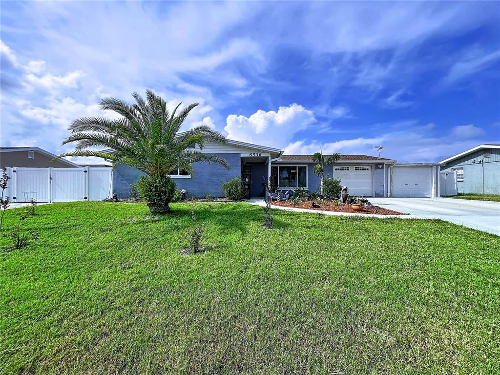 A single-story blue brick house with a palm tree and a large front lawn — 6536 LEESIDE ISLE, HUDSON, FL