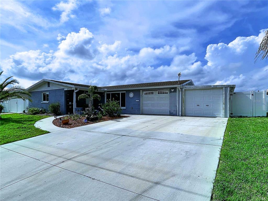 A single-story blue brick house with a concrete driveway and two garage doors — 6536 LEESIDE ISLE, HUDSON, FL