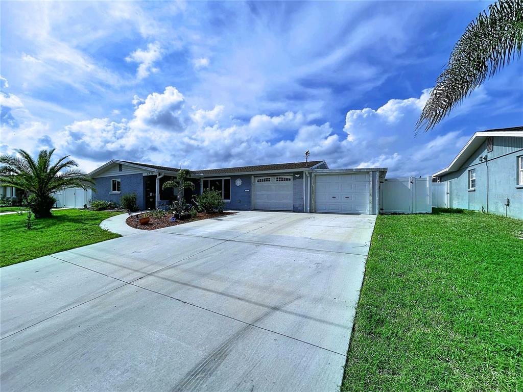 A single-story house with a blue exterior, a concrete driveway, and a two-car garage — 6536 LEESIDE ISLE, HUDSON, FL