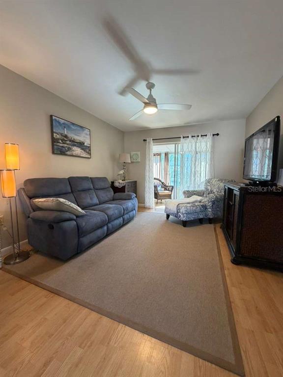 A living room features a blue sofa, a patterned armchair, and a large area rug — 1832 SUNNY DRIVE UNIT D-32, BRADENTON, FL